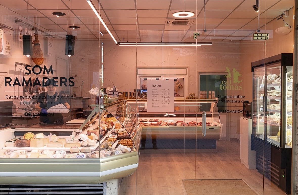 Inside a butcher's shop, with a full counter and a person serving.